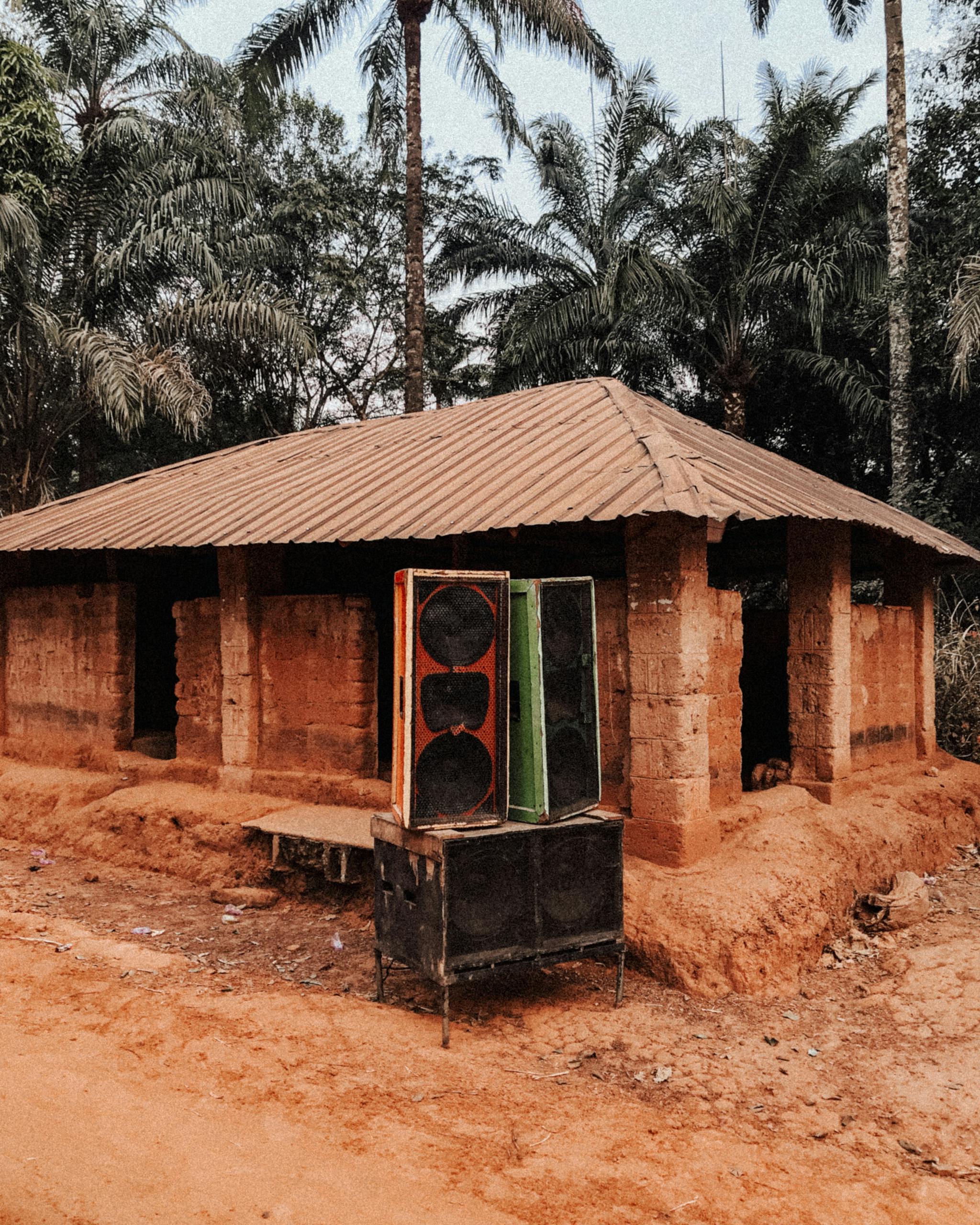 An old rustic house with large speakers outside, set in a village in Enugu, Nigeria.